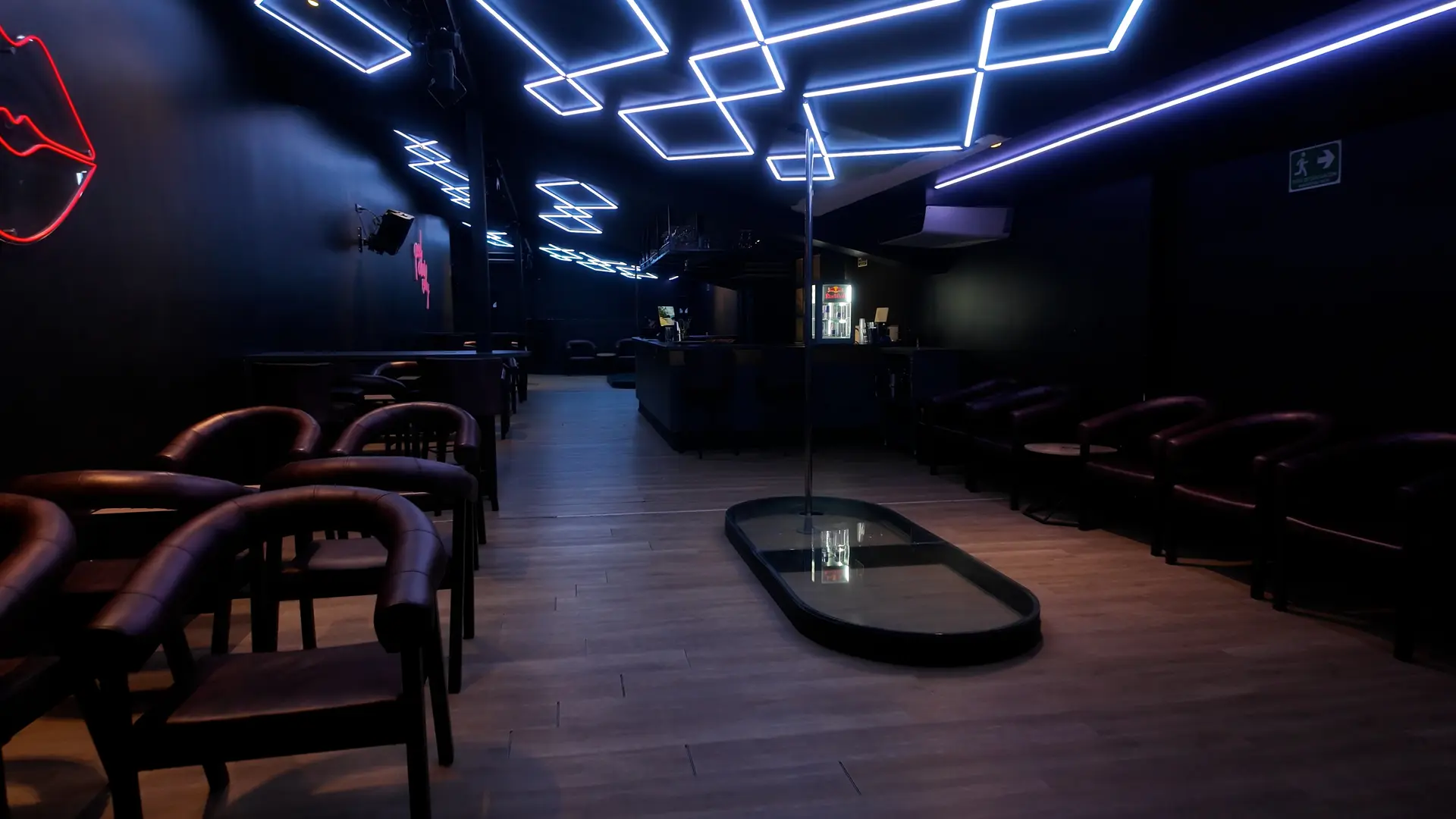 Main room at Club Fase II with a blue neon ceiling, leather chairs and a pole stage, El Poblado, Medellín